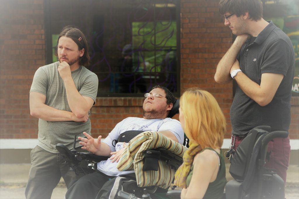 Disabled director, Dominick Evans, disabled editor, Kasey Faye, cinematographer Kyle Wilkinson, and AD, Randy Miller, look on while discussing set up for a scene during shooting of the film, trip.